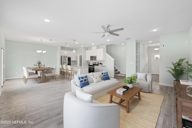 living room featuring ceiling fan with notable chandelier