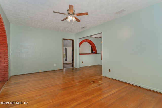 empty room featuring ceiling fan, light hardwood / wood-style flooring, and a textured ceiling