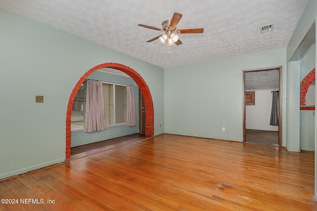 empty room featuring ceiling fan, light hardwood / wood-style floors, and a textured ceiling