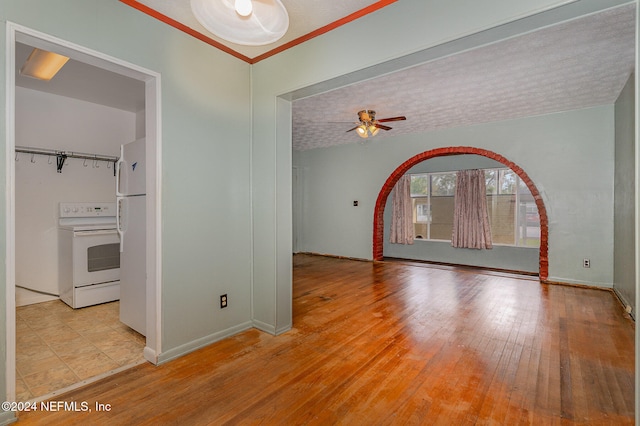 spare room featuring ceiling fan, light wood-type flooring, and a textured ceiling