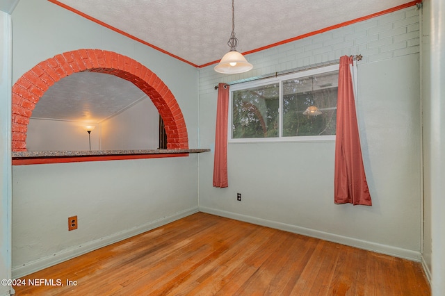 spare room with crown molding, hardwood / wood-style floors, and a textured ceiling