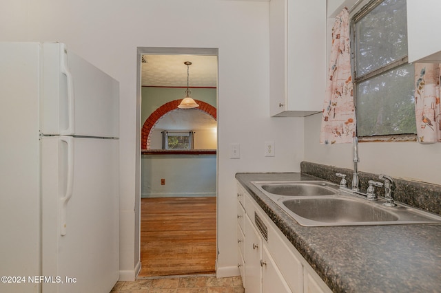 kitchen featuring white cabinetry, sink, hanging light fixtures, light hardwood / wood-style flooring, and white refrigerator