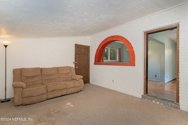 unfurnished living room featuring carpet flooring, a textured ceiling, brick wall, and lofted ceiling