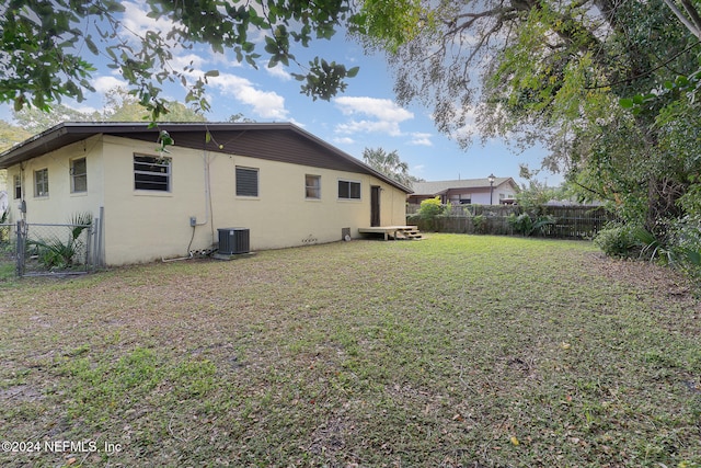 back of house featuring central air condition unit and a yard