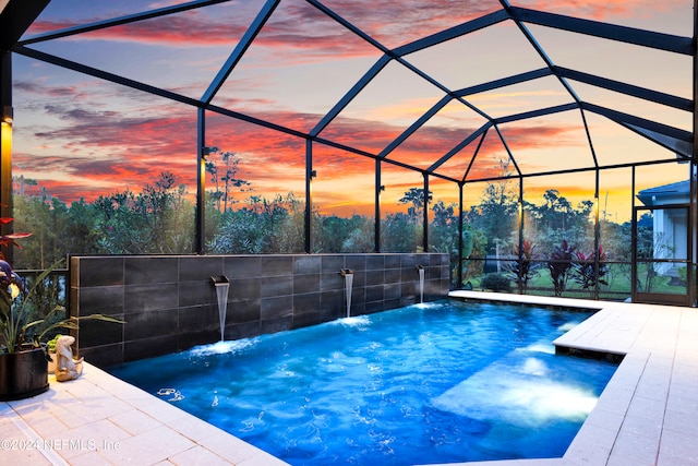 pool at dusk with a lanai and pool water feature