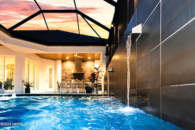 pool at dusk featuring a lanai