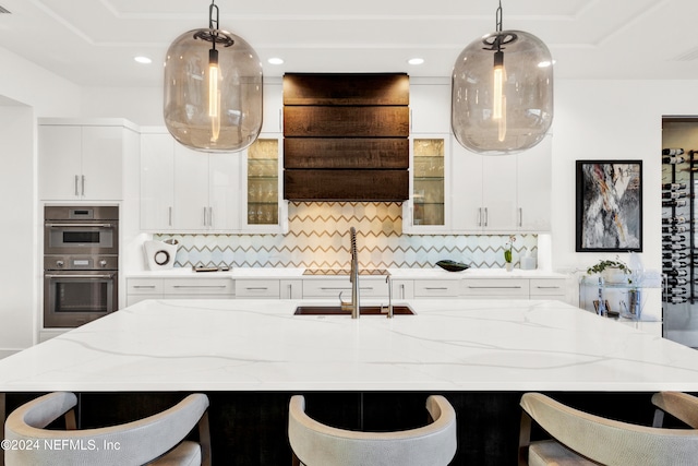 kitchen with white cabinets, decorative light fixtures, ventilation hood, and stainless steel double oven