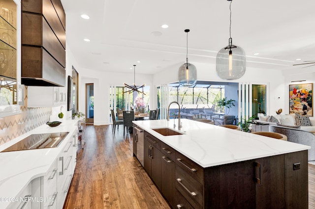 kitchen with hardwood / wood-style floors, white cabinetry, sink, and hanging light fixtures