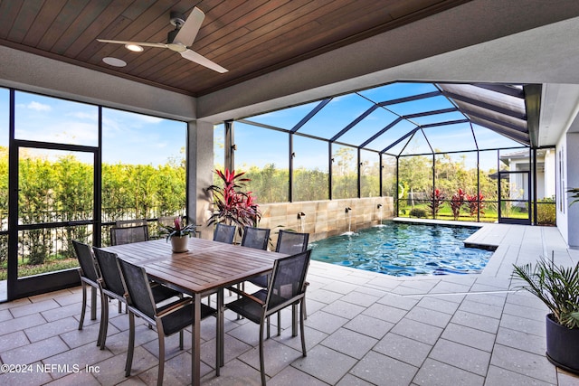 view of pool featuring pool water feature, ceiling fan, a patio area, and glass enclosure