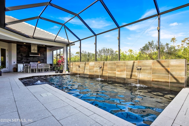 view of swimming pool with pool water feature, glass enclosure, and a patio area