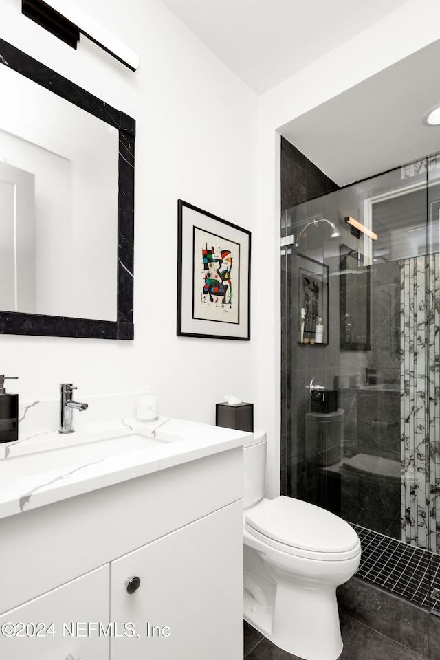 bathroom featuring tile patterned floors, vanity, toilet, and a shower with door