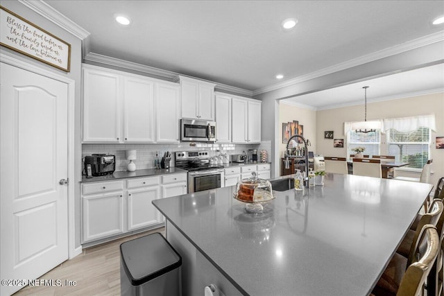 kitchen featuring stainless steel appliances, white cabinetry, sink, and a kitchen bar