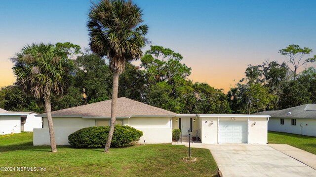 ranch-style house with a garage and a yard