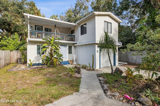 view of front facade with a garage, a balcony, concrete driveway, and fence