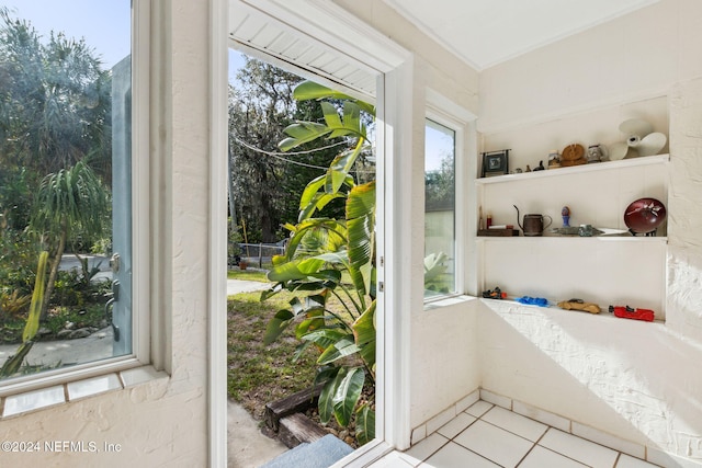 doorway featuring light tile patterned floors and ornamental molding