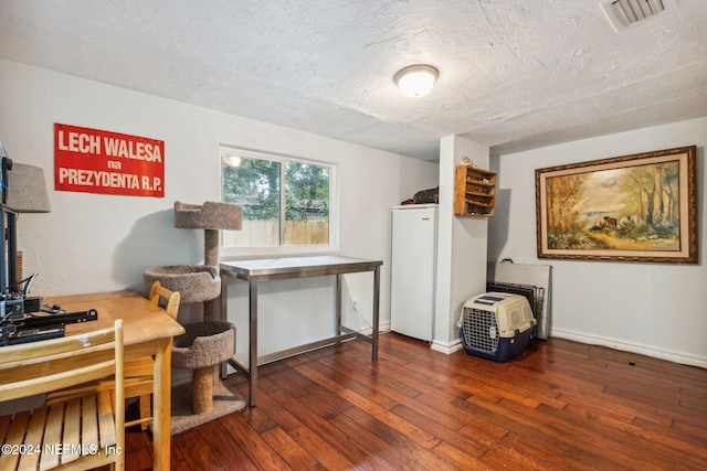 home office featuring visible vents, a textured ceiling, baseboards, and hardwood / wood-style floors