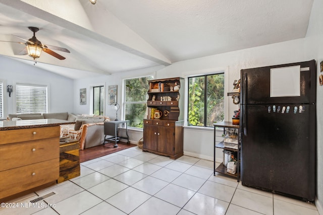 interior space featuring baseboards, lofted ceiling, light tile patterned flooring, and freestanding refrigerator