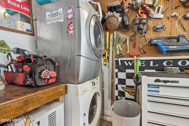 laundry area with a workshop area and stacked washer and dryer