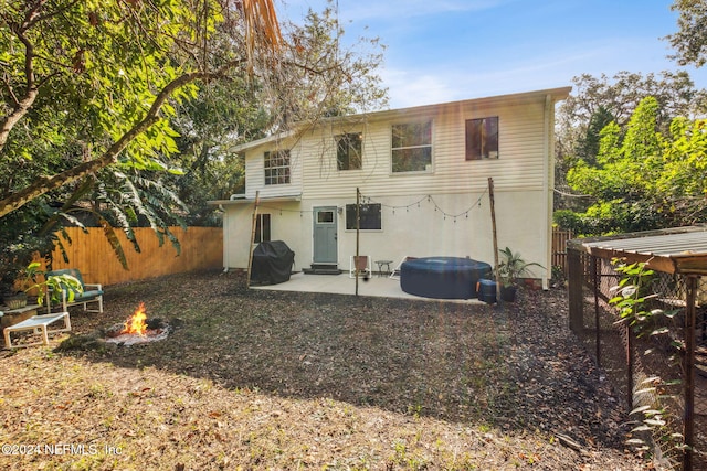 rear view of property with a patio, stucco siding, fence private yard, and an outdoor fire pit