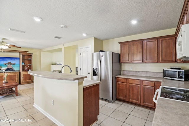 kitchen featuring a textured ceiling, an island with sink, stainless steel appliances, and light tile patterned floors