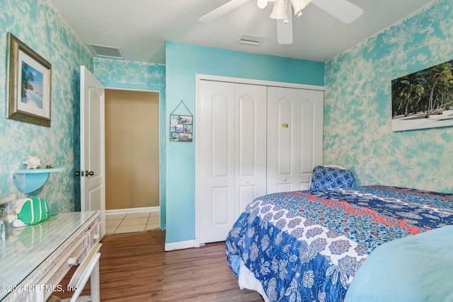 bedroom with a closet, ceiling fan, hardwood / wood-style floors, and a textured ceiling