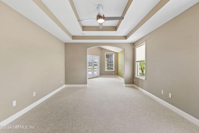 carpeted spare room featuring a tray ceiling and ceiling fan