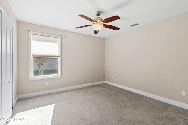 carpeted spare room featuring ceiling fan