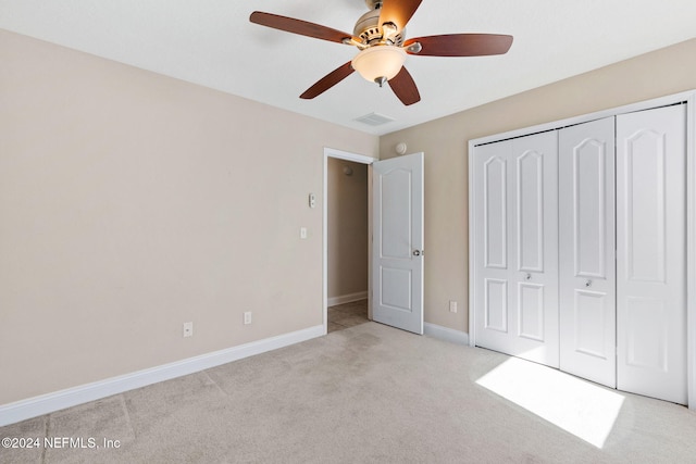 unfurnished bedroom with ceiling fan, a closet, and light carpet