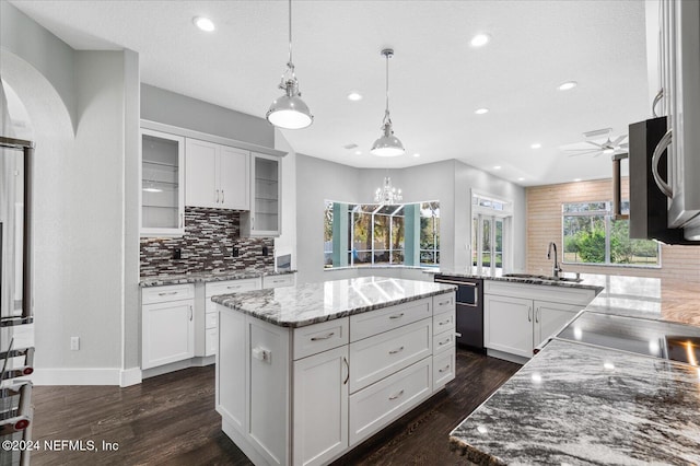 kitchen with a kitchen island, white cabinetry, decorative light fixtures, sink, and dishwasher