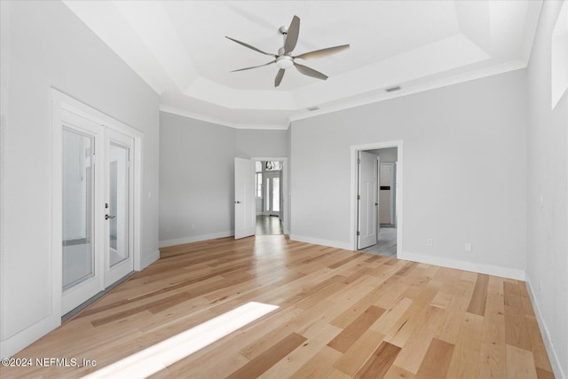 unfurnished room with light hardwood / wood-style floors, ceiling fan, and a tray ceiling