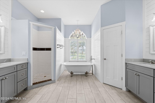 bathroom with a notable chandelier, hardwood / wood-style flooring, vanity, and plus walk in shower