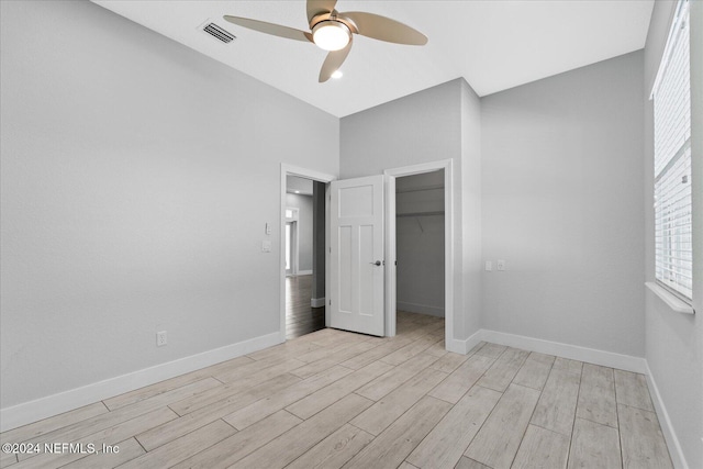 unfurnished bedroom with light hardwood / wood-style flooring, ceiling fan, a spacious closet, and a closet