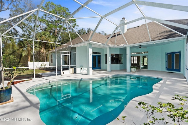 view of swimming pool with glass enclosure, french doors, ceiling fan, and a patio