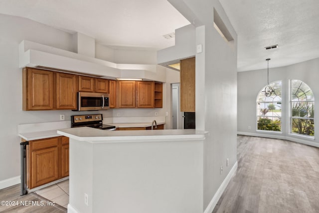 kitchen featuring black electric range, kitchen peninsula, hanging light fixtures, and light hardwood / wood-style floors