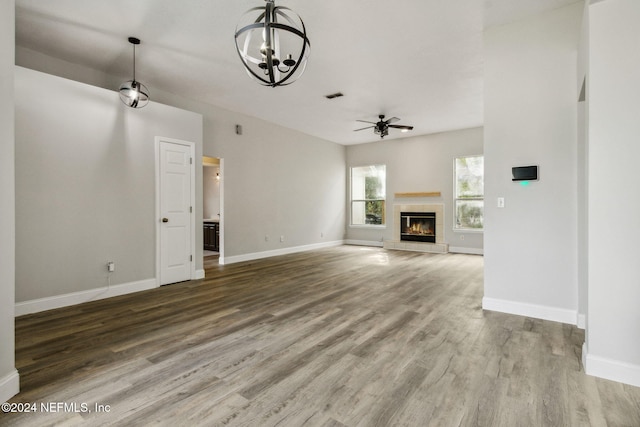 unfurnished living room featuring hardwood / wood-style floors, a fireplace, and ceiling fan with notable chandelier