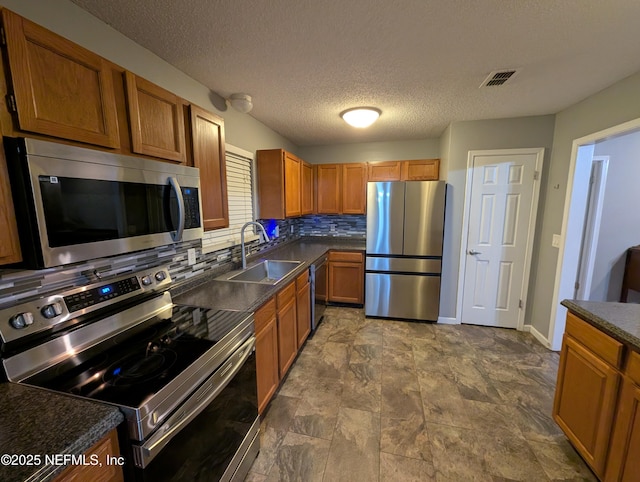 kitchen with tasteful backsplash, appliances with stainless steel finishes, sink, and a textured ceiling