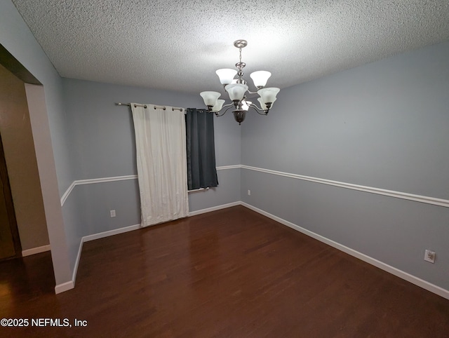 unfurnished room with dark hardwood / wood-style floors, a notable chandelier, and a textured ceiling