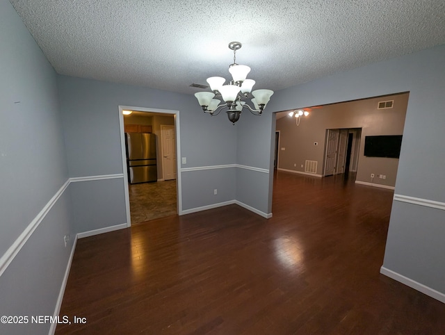 unfurnished dining area featuring dark hardwood / wood-style flooring, a textured ceiling, and a chandelier