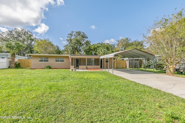 ranch-style home featuring a front yard, a sunroom, and a carport