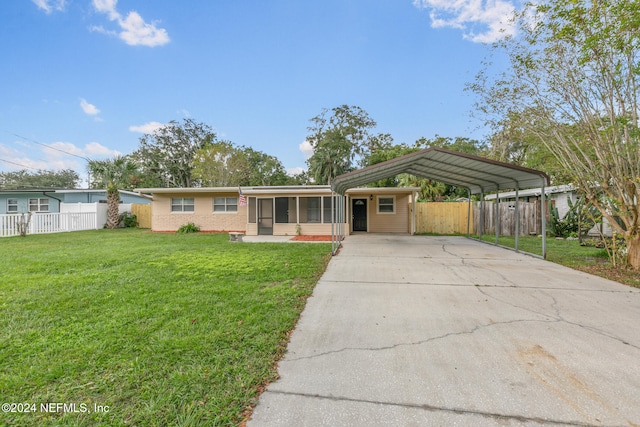 single story home with a front yard, a sunroom, and a carport