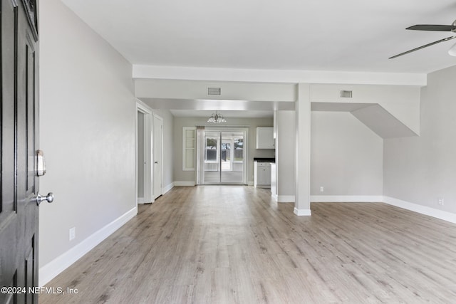 unfurnished living room featuring ceiling fan with notable chandelier and light hardwood / wood-style flooring