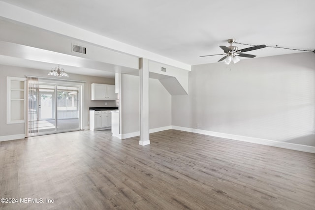 unfurnished living room featuring ceiling fan with notable chandelier and wood-type flooring