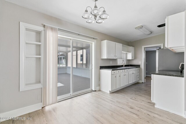 kitchen featuring white cabinetry, light hardwood / wood-style floors, sink, and a chandelier