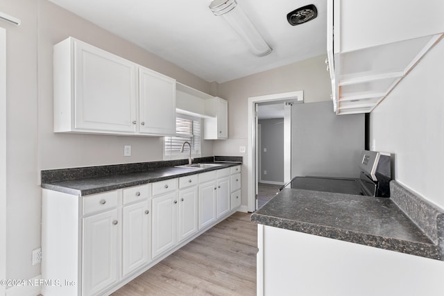 kitchen with white cabinets, light hardwood / wood-style floors, stove, and sink