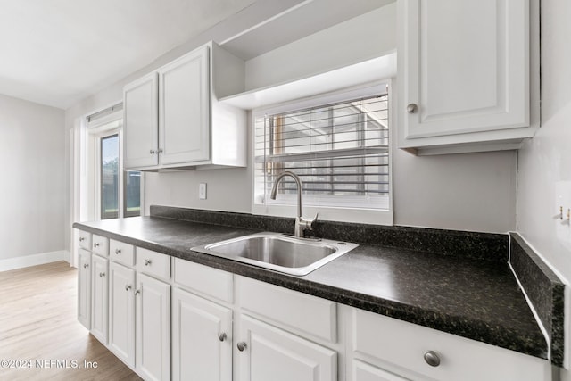 kitchen featuring white cabinetry, sink, and light hardwood / wood-style flooring