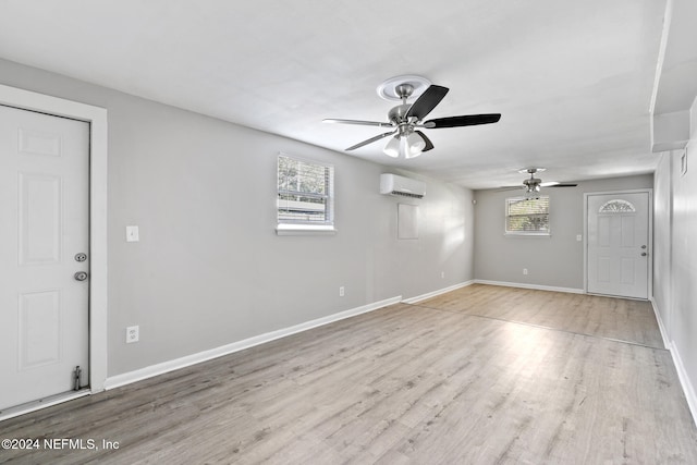 interior space with an AC wall unit, light hardwood / wood-style floors, and ceiling fan