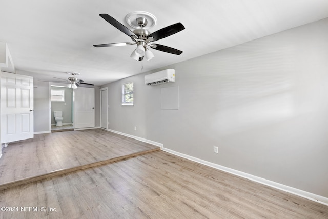 spare room with light hardwood / wood-style floors, ceiling fan, and an AC wall unit