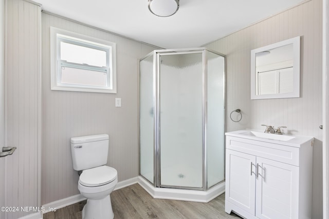 bathroom with toilet, vanity, hardwood / wood-style floors, and a shower with door