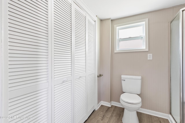 bathroom featuring hardwood / wood-style flooring, a shower with shower door, and toilet