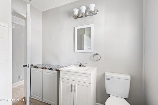 bathroom with toilet, vanity, and hardwood / wood-style flooring